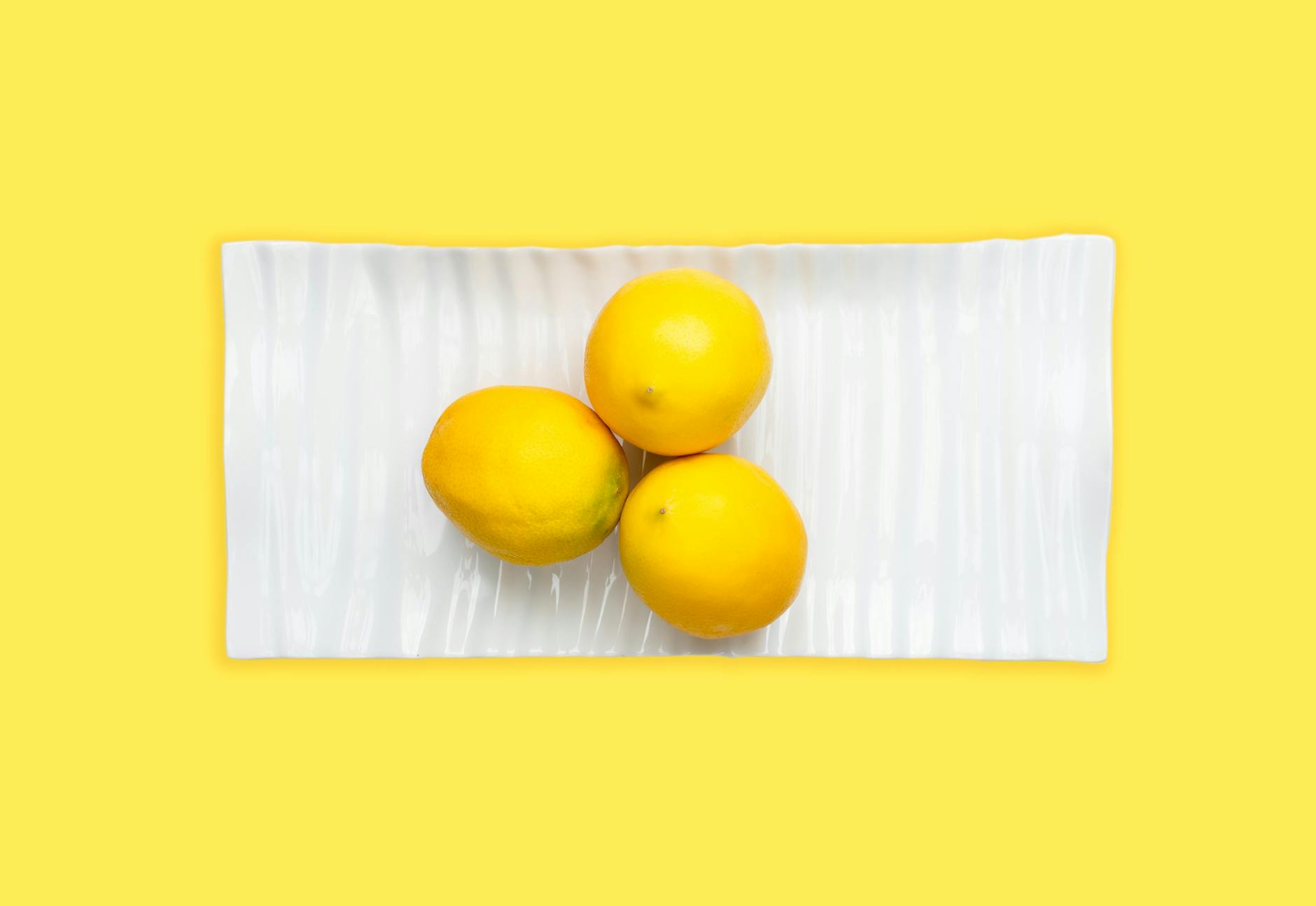 Bright yellow silicone vibrator surrounded by fresh fruit on a cheerful background