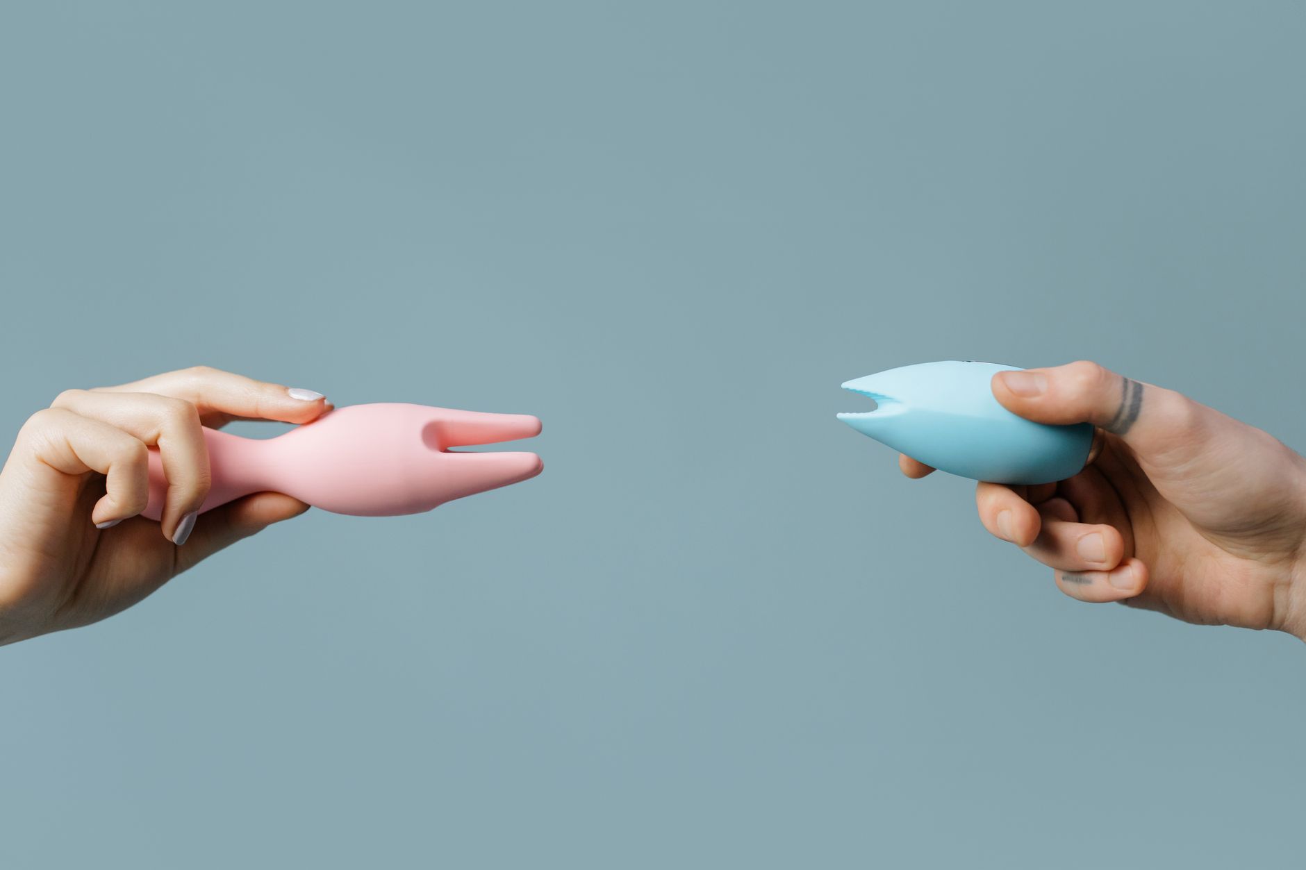 Two hands holding vibrators against a pastel background, symbolizing fresh starts and renewed intimacy.