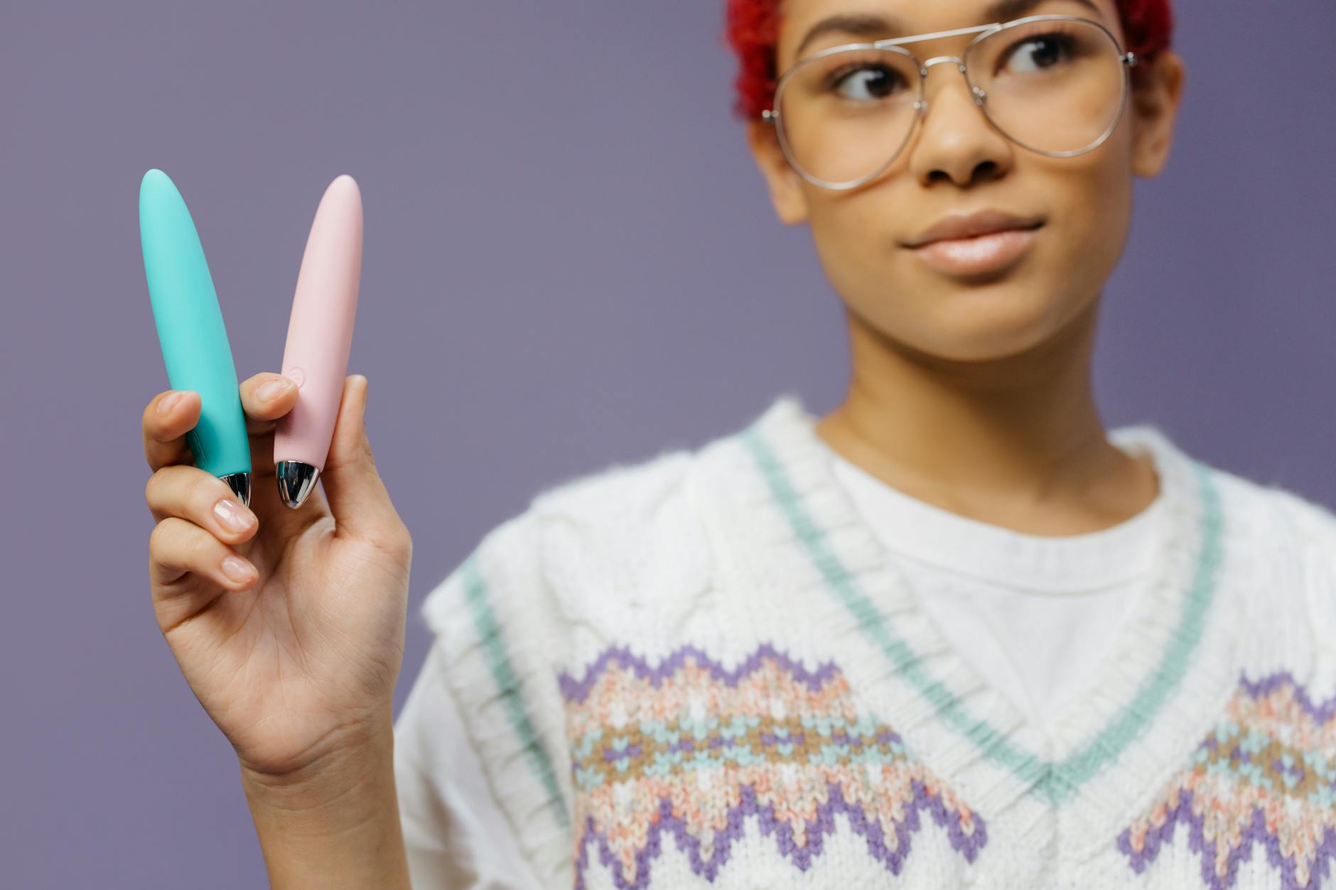 Close-up of colorful vibrators held against a purple background, representing modern intimacy tools for long-distance couples